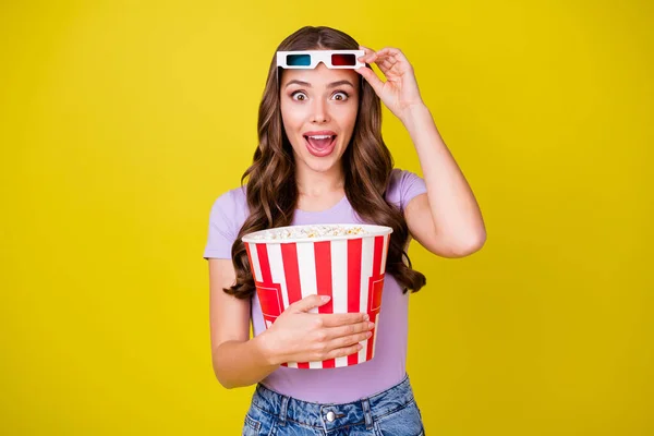 Portrait of pretty amazed cheerful wavy-haired girl wearing funky modern eyewear eating corn watching film isolated bright yellow color background — Stock Photo, Image
