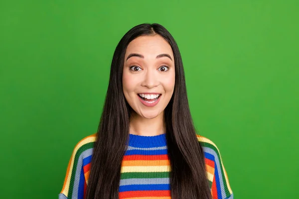 Close-up portret van aantrekkelijke verbaasd vrolijk meisje dragen gestreepte pullover nieuws reactie geïsoleerd over helder groene kleur achtergrond — Stockfoto