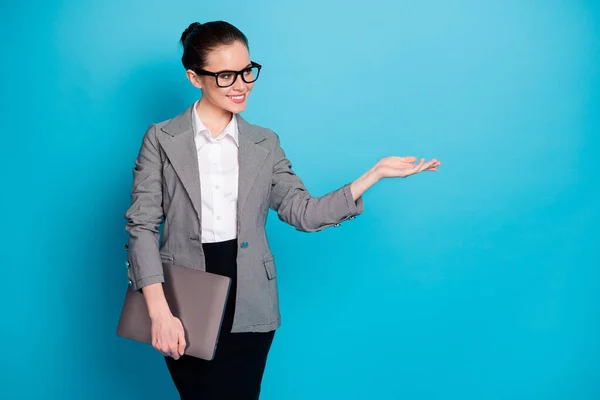 Retrato de atraente elegante menina alegre especialista transportando laptop segurando na palma do espaço de cópia conselho isolado cor azul brilhante fundo — Fotografia de Stock