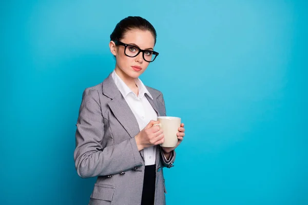 Foto de chica confiada financista mantenga caliente capuchino taza desgaste traje de chaqueta gris aislado sobre fondo de color azul — Foto de Stock