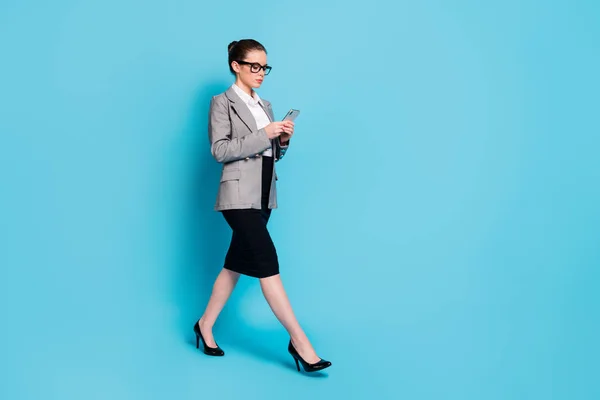 Полная длина профиля боковой фото босс девушка пойти использовать смартфон носить куртку юбка изолированный синий цвет фона — стоковое фото