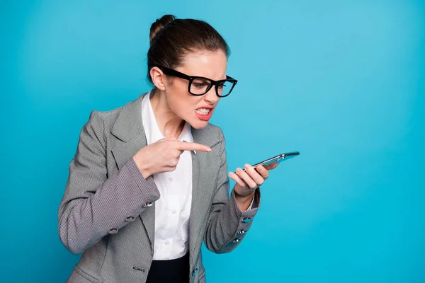 Menina furiosa executivo uso smartphone ponto dedo alto alto-falante desgaste casaco isolado azul cor fundo — Fotografia de Stock