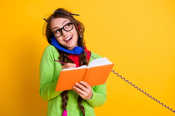 Close-up retrato de menina alegre atraente funky falando por telefone escrevendo tarefa em casa discutindo isolado cor amarela brilhante fundo — Fotografia de Stock