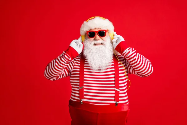 Portrait of his nice handsome bearded cheerful cheery Santa father listening music pop rock soul jazz different single isolated over bright vivid shine vibrant red color background — Stok Foto