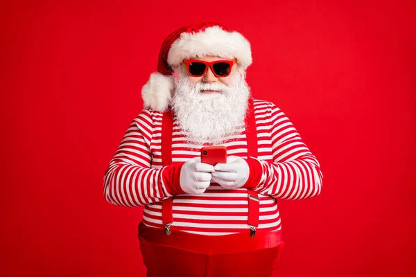 Potret nya dia tampan menarik ceria terfokus berjenggot berjenggot abu-abu-rambut Santa menggunakan perangkat gadget aplikasi 5g roaming terisolasi di cerah cerah bersinar latar belakang warna merah — Stok Foto
