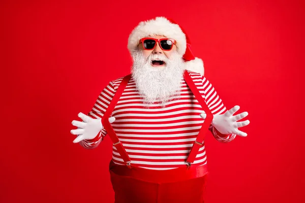 他的画像，他那漂亮漂亮、迷人、孩子气、开朗、喜庆、灰白头发的圣诞老人，戴着手套，挂着有趣的吊带，与明亮、生动、充满活力的红色背景隔离在一起 — 图库照片