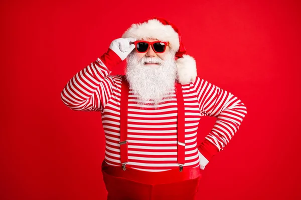 他的画像，他那俊俏俊俏、快乐、灰白头发的圣诞老人，戴着动人的太阳镜，冬天喜庆的节日气氛，与明亮鲜亮的红色背景格格不入 — 图库照片