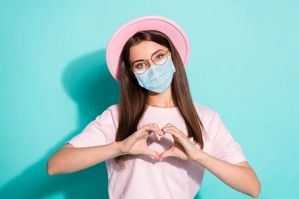 Foto van positieve jonge dame maken vingers hart tonen eindeloze liefde symbool slijtage masker geïsoleerde turquoise kleur achtergrond — Stockfoto