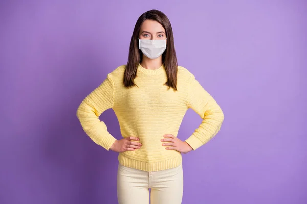 Foto portret van jonge vrouw staan handen taille dragen gezicht griep masker quarantaine geïsoleerde paars gekleurde achtergrond — Stockfoto
