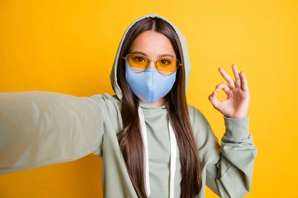 Foto di bambino mostra dito ok simbolo stile di vita elegante felpa con cappuccio usura blu tessuto maschera isolata su sfondo di colore giallo — Foto Stock