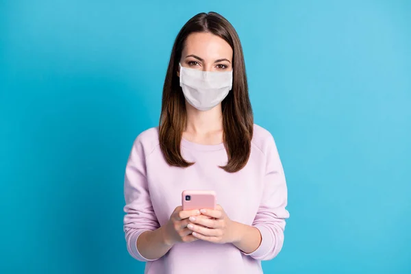 Foto da menina segurar telefone desgaste branco máscara facial isolado azul cor de fundo — Fotografia de Stock