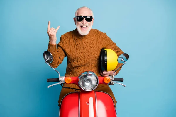 Portrait of his he nice attractive funky cheerful cheery cool naughty bearded grey-haired man hipster sitting on moped showing horn symbol isolated over blue pastel color background — Stock Photo, Image