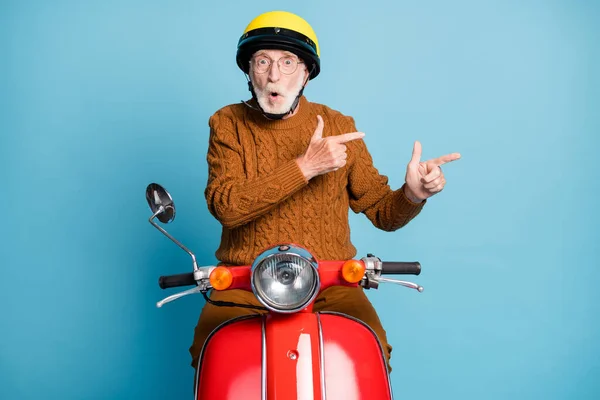 Portrait of his he nice atrakted amazned stunned stunned bearded grey-haired man riding moped showing copy space black Friday look idea solution isolated over blue pastel color background — Stok Foto