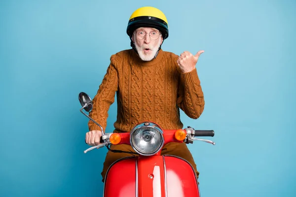 Retrato dele ele agradável atraente atordoado espantado barbudo homem de cabelos grisalhos pai equitação ciclomotor apontando polegar de lado cópia espaço atenção solução isolada sobre azul pastel cor fundo — Fotografia de Stock