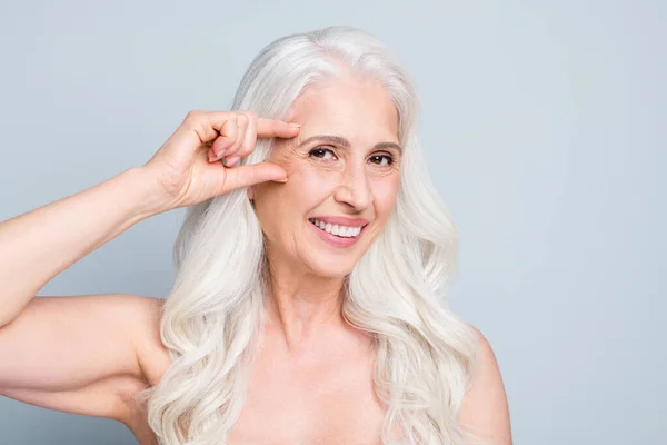 Foto van mooie oude dame met resultaten contouren gezichtsvorm hold arm in de buurt van ooglijn geïsoleerde grijze kleur achtergrond — Stockfoto
