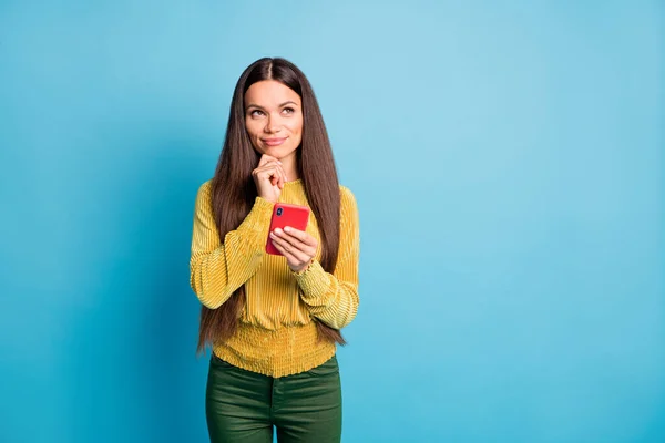 Foto retrato de mujer soñadora tocando la barbilla con el dedo sosteniendo el teléfono rojo en una mano aislada sobre fondo de color azul pastel con espacio en blanco —  Fotos de Stock