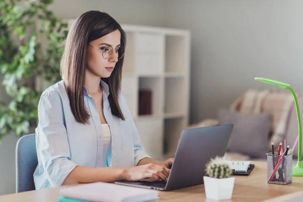 Foto de una joven dama seria sentarse manos tecleando teclado portátil usar gafas camisa en casa oficina en interiores — Foto de Stock