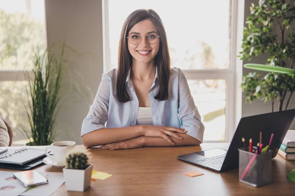 Фото прекрасной леди сидеть стол руки стол блестящая улыбка смотреть камера носить очки рубашку в домашнем офисе в помещении — стоковое фото