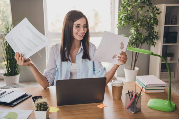 Foto de la encantadora señora bonita sentarse mesa mantener papeles mirar gráficos usar gafas camisa en casa oficina en interiores —  Fotos de Stock