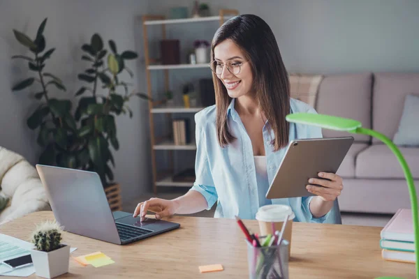 Foto van mooie schattige meisje zitten tafel look scherm computer hold tablet slijtage bril shirt in huis kantoor binnen — Stockfoto