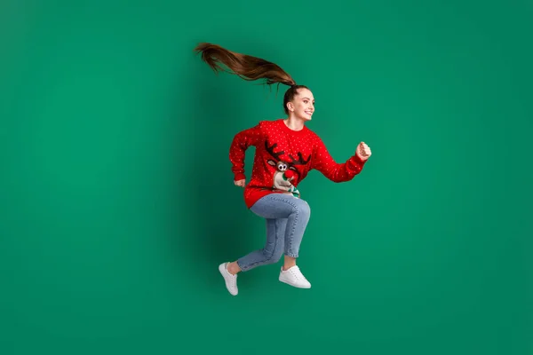 Фотографія повного профілю тіла божевільної красивої леді стрибає високий поспіх магазин торговий центр сезону x-mas купити подарунки споживання одягу червоний потворний светр джинси взуття ізольовані зелений колір фону — стокове фото