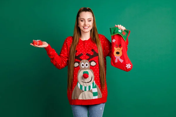 Photo of pretty charming lady hold newyear stocking x-mas present show little giftbox hold open hand arm jewelry from boyfriend wear red ugly ornament pullover isolated green color background — Stock Photo, Image