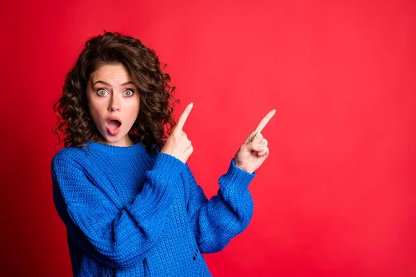 Foto von niedlichen charmante Dame wellige Frisur heben die Hände direkt Zeigefinger nach oben leeren Raum offenen Mund Schock verrückt Gesicht tragen blau gestrickte Pullover Pullover isoliert rote Farbe Hintergrund — Stockfoto