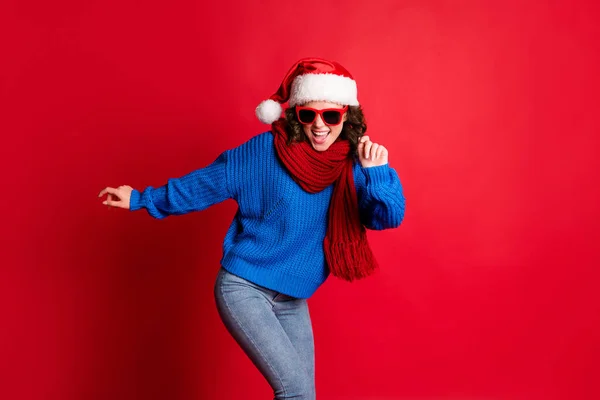 Le concept du réveillon du Nouvel An. Photo portrait fille festive dansant portant des lunettes écharpe santa chapeau pull bleu isolé sur fond rouge vif — Photo