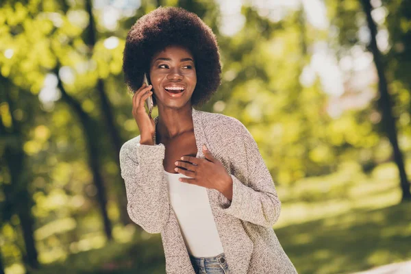 Foto van positieve afro-Amerikaanse meisje call talk smartphone in groene stad buiten park dragen gebreide trendy trui — Stockfoto