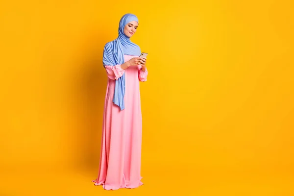 Full length dimensione del corpo vista di bella bella elegante focalizzata muslimah indossare hijab utilizzando dispositivo app 5g isolato colore giallo lucido sfondo — Foto Stock