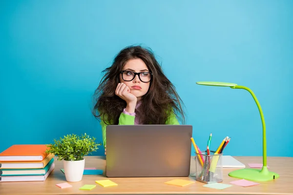Portrait de fille de lycée ennuyée assis bureau regarder copyspace porter chemise verte isolé sur fond de couleur bleue — Photo