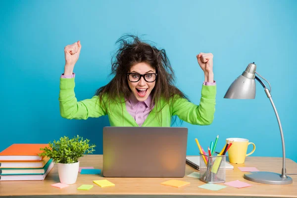 Portret van blij meisje zitten tafel studie remote laptop verhogen vuisten schreeuwen geïsoleerde blauwe kleur achtergrond — Stockfoto