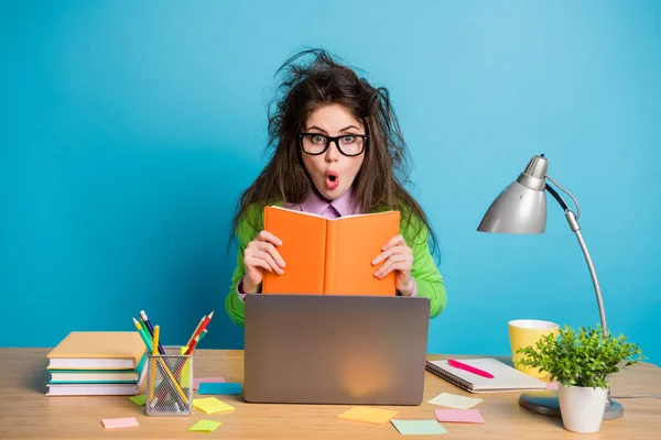 Portrét užaslé hnědé chaotické vlasy dívka sedět stůl držet copybook nosit zelenou košili izolované modré barvy pozadí — Stock fotografie