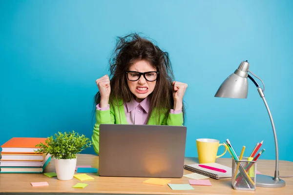 Portrait de fille furieuse assis table travail ordinateur portable erreur concept porter chemise verte isolé sur fond de couleur bleue — Photo