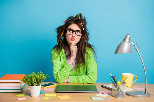 Pensive Mädchen Bleistiftfrisur sitzen Schreibtisch berühren Kinn Finger suchen Kopierraum denken isoliert blaue Farbe Hintergrund — Stockfoto