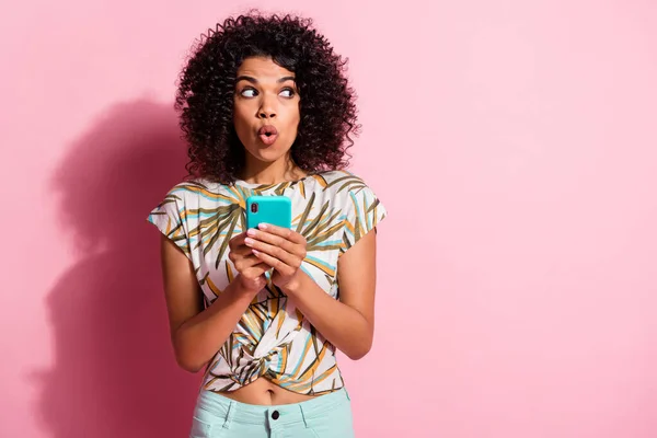 Foto retrato de mujer sorprendida sosteniendo el teléfono cyan en dos manos aisladas sobre fondo de color rosa pastel con espacio en blanco — Foto de Stock