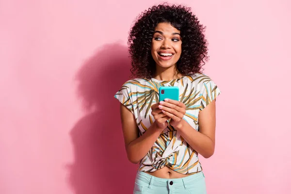Fénykép portré izgatott lány gazdaság telefon két kezében nézi üres hely elszigetelt pasztell rózsaszín színű háttér — Stock Fotó