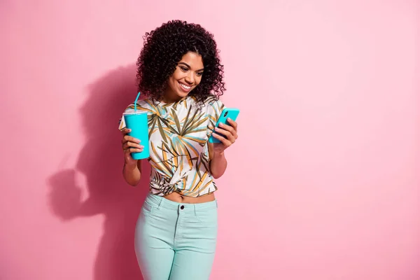 Foto portret van meisje met telefoon papieren beker in handen sms 'en geïsoleerd op pastel roze gekleurde achtergrond — Stockfoto