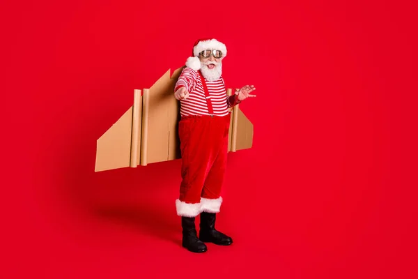 退休老人滑稽的全长照片爷爷纸翼直指选择你送的助手穿圣诞服装吊袜带太阳镜靴条纹衬衫帽孤立的红色背景 — 图库照片