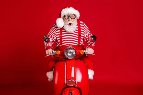 Retrato dele ele bonito espantado impressionado barbudo Pai Natal equitação ciclomotor entrega presentes tradição viagem velocidade rápida pressa pressa isolado brilhante vívido brilho vibrante cor vermelha fundo — Fotografia de Stock