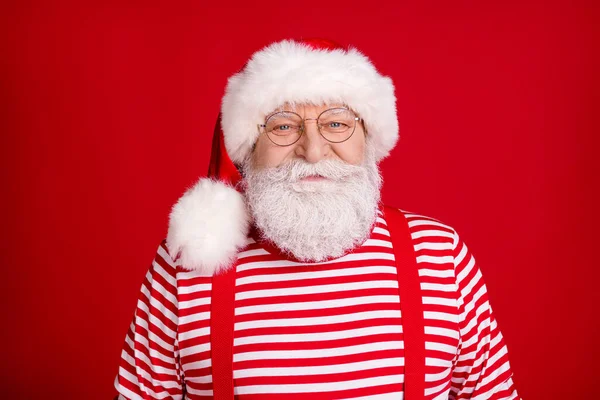 Фото пенсіонера, який посміхається чекати опівночі новорічного святкування готуйте прикрасити будинок одягом підвіски для костюмів Санта, показує смугасті головні убори сорочки ізольований червоний колір фону — стокове фото