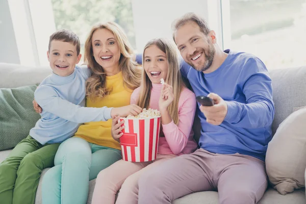 Photo of comfort dream people family mom dad two little kids sit sofa watch movie eat pop corn in house in doors — Zdjęcie stockowe