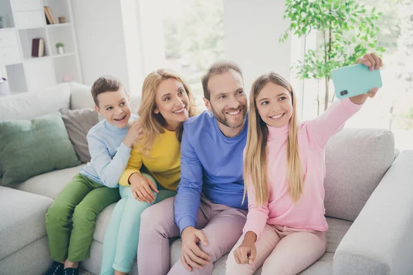 Foto van positieve familie mensen moeder vader zitten bank kind meisje maken selfie op smartphone in huis binnen — Stockfoto