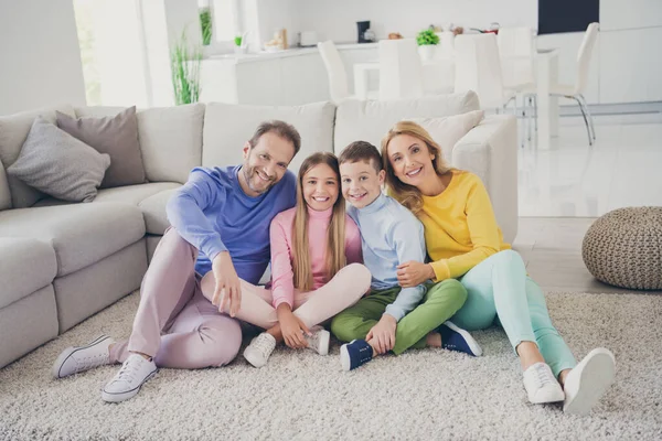 Foto de corpo inteiro de família positiva mãe pai dois filhos sentar tapete em casa dentro de casa — Fotografia de Stock