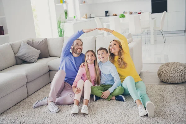 Full size foto van mensen familie zitten vloer mam vader houd handen boven kijken omhoog kleine kinderen in huis binnen — Stockfoto