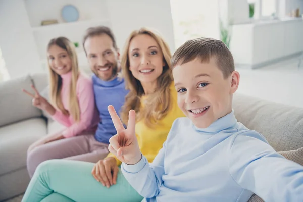 Foto de familia positiva personas se sientan acogedor sofá mamá papá tomar selfie dos niños hacen v-signo en la casa en el interior — Foto de Stock