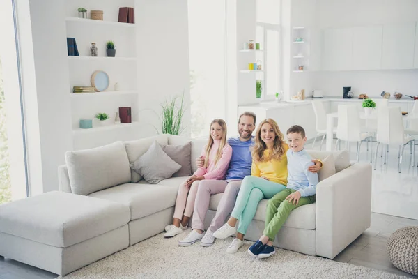 Celá tělo foto pozitivní rodina maminka táta dvě děti chlapec dívka objetí sedět gauč v obývacím pokoji dům uvnitř — Stock fotografie