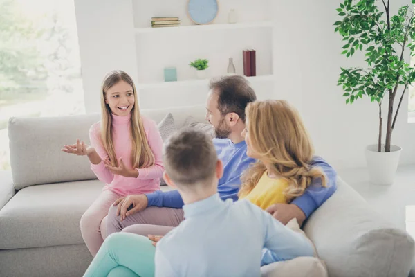 Foto van positief schattig kind meisje zitten bank praten nieuws met mama papa broer in huis binnen — Stockfoto