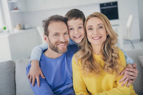 Photo of positive boy hug loving mother father sit comfy divan in house indoors — Stock Photo, Image
