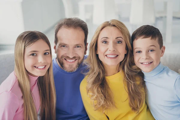 Фото ідилічної сім'ї мама тато і двоє дітей хлопчик дивляться в камеру зубна посмішка сидить на дивані в будинку в приміщенні — стокове фото